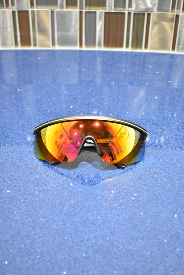 Brand new black framed sunglasses with BluBlocker orange lenses, offering UV protection. Stylish and durable design.