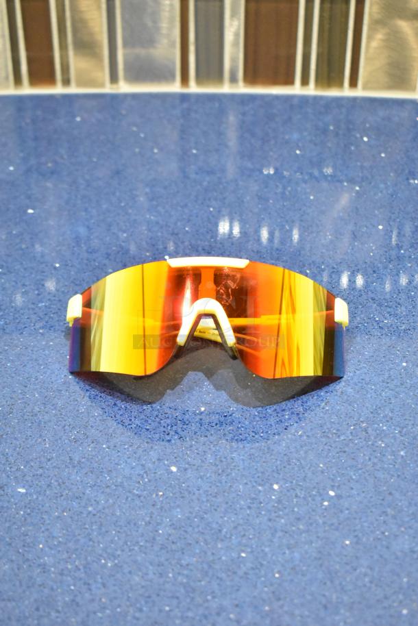 Brand new yellow framed sunglasses with BluBlocker orange lens on blue surface.
