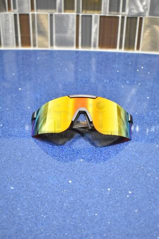 Brand new gray framed sunglasses with BluBlocker orange lenses on a blue surface.