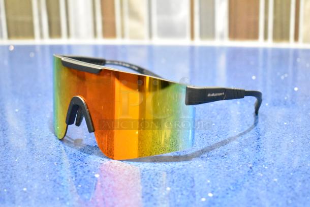 Brand new gray framed sunglasses with BluBlocker orange lens on blue surface.