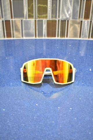 Brand new white-framed sunglasses with BluBlocker orange lenses on a blue surface.