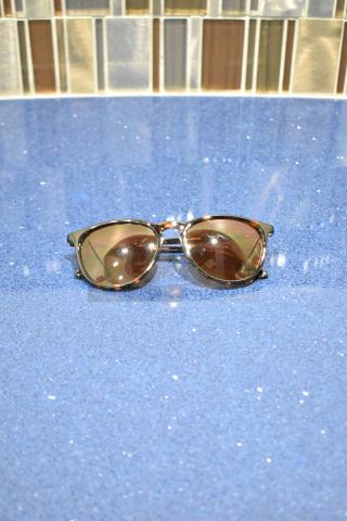 Brand new tortoise shell framed sunglasses with BluBlocker brown lenses, glossy finish, on a sparkly blue surface.