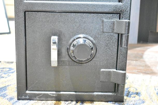 Black single compartment drop safe with dial lock; no combination included, sturdy construction, minor scuffs.