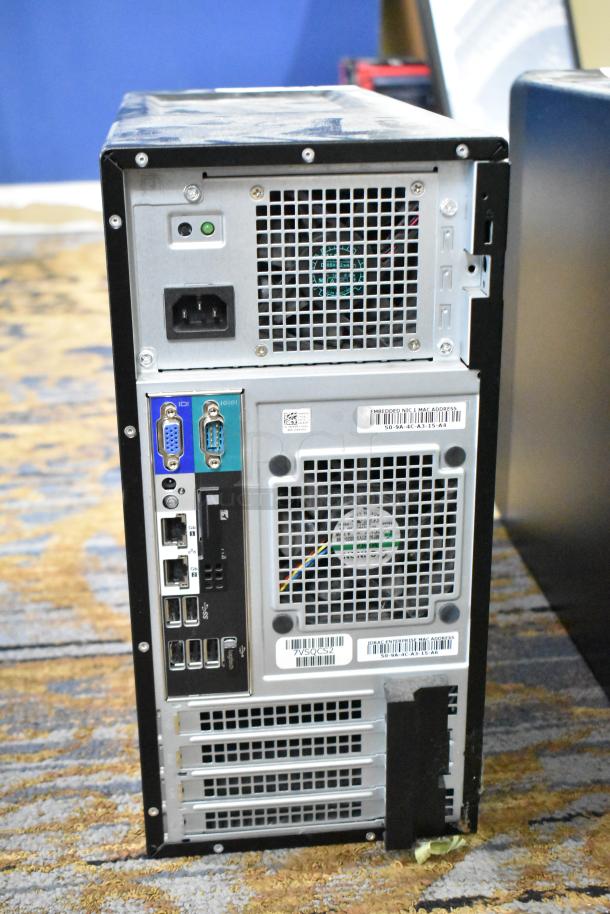 Dell PowerEdge T130 computer tower, no hard drive. Rear view showing ports and ventilation fans, barcode labels visible.