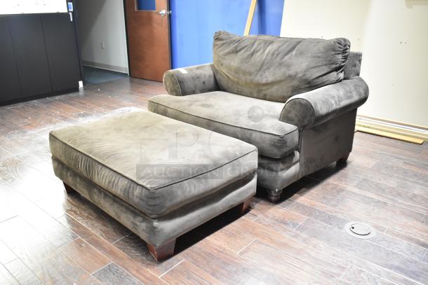 Gray armchair with ottoman, soft fabric upholstery, rolled arms, wood legs, in good condition. Ideal for comfortable seating.