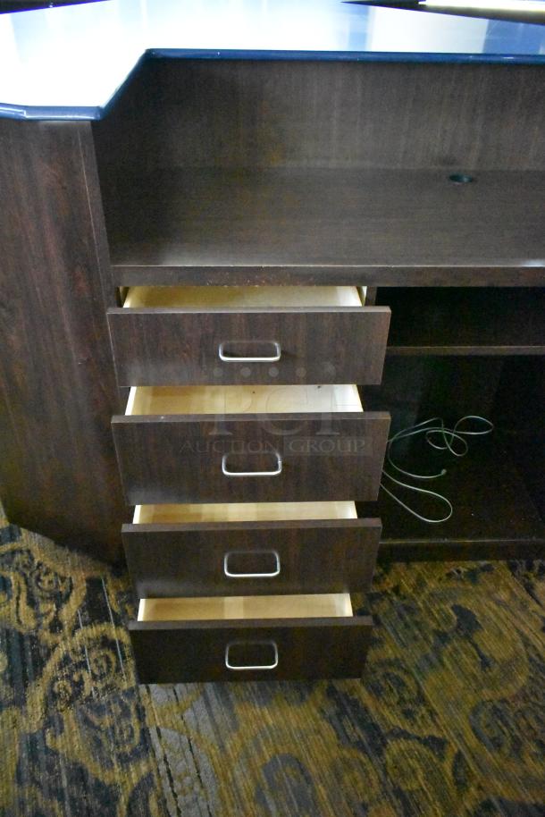 Wooden counter with five open drawers and one door, dark finish. Features metal handles, moderate wear, visible wire inside.