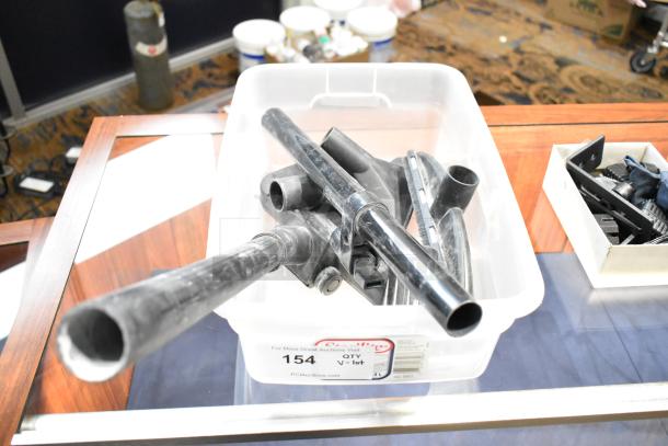 Plastic tub filled with black vacuum attachments and miscellaneous pieces. Auction label indicates "154 QTY V-lot" from PCI Auctions.
