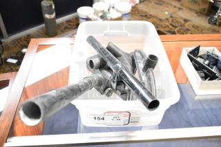 Plastic tub filled with black vacuum attachments and miscellaneous pieces. Auction label indicates "154 QTY V-lot" from PCI Auctions.