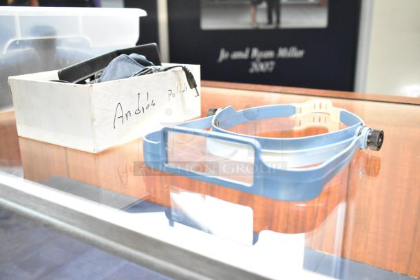 Lot of various items including a blue headband, box with label "Andres Pulido," and assorted pieces in container.