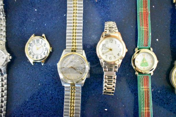 Lot of five assorted watches on display, featuring several styles and band types, including a gold-toned Pulsar with day display.