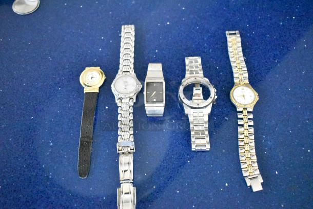 Five items including four various watches and a watch band on a blue background, showing mixed metal finishes and styles.