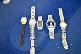 Five items including four various watches and a watch band on a blue background, showing mixed metal finishes and styles.