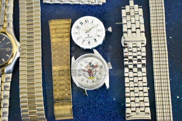Assorted watches and watch bands, including a Mickey Mouse watch, various metal bands, and a gold-toned watch.