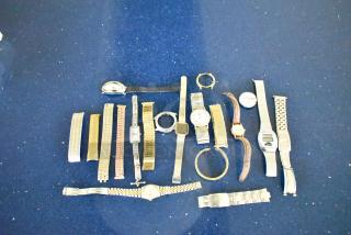 32 assorted watches and watch bands on a blue surface. Each item varies in style and condition, showcasing diverse options.