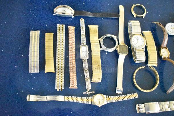 32 assorted watches and bands, varying styles and conditions, on display. Includes metal, leather, and fabric materials.