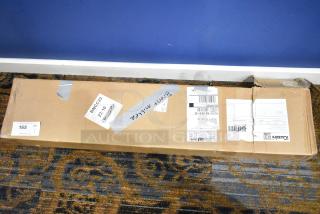 Cardboard box containing iGuzzini Lido Lighting fixture, sealed with shipping labels and duct tape, resting on carpet.