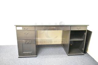Wooden desk with five drawers, dark finish, visible wear. Features a side cabinet with shelves. Label reads "160".