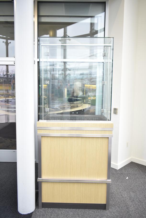 Wooden corner jewelry display case with glass top, oak finish, metal accents, and lockable doors. Buyer must remove.