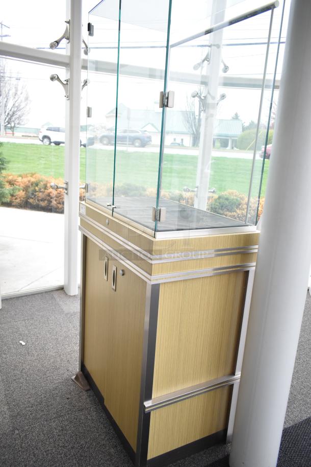 Wooden corner-style jewelry display case with glass panels, metal trim, and storage cabinets. Good condition. Buyer removal required.