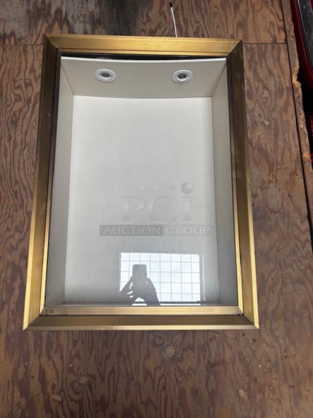 Gold-framed vertical wall display case with glass front, interior lighting, and reflective back panel, in good condition.