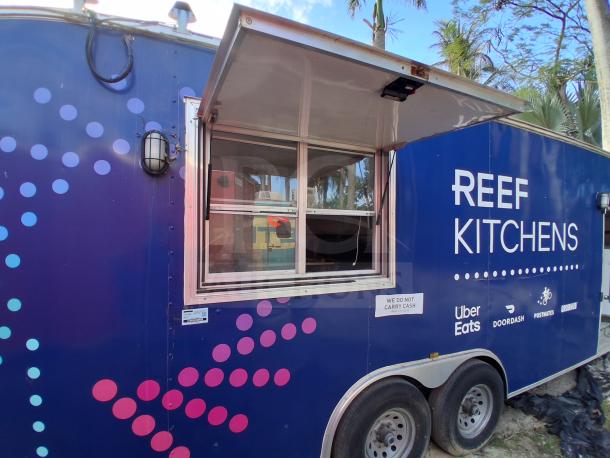Blue food trailer with grease hood, Royal Range, Avantco griddle, gas fryer, and four-unit refrigeration. Branded "Reef Kitchens."