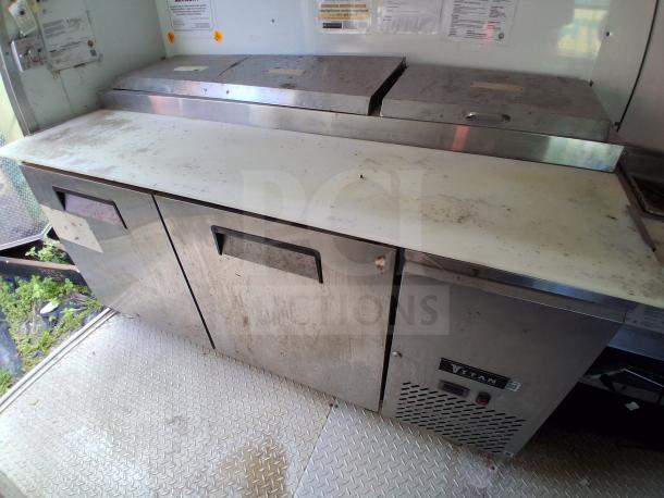 Food trailer interior showing refrigeration units, stainless steel surfaces, and two compartments. Some surface wear visible.