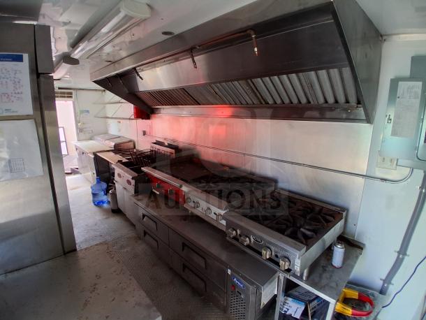 Food trailer kitchen with grease hood, Royal Range, Avantco griddle, Avantco gas fryer, and four-unit refrigeration.