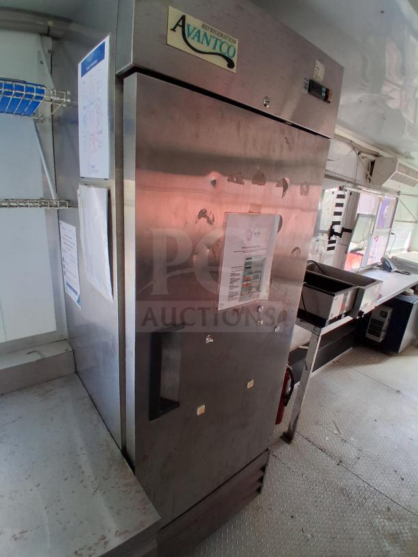 Food trailer interior with Avantco refrigeration unit, cooking griddle, gas fryer, and grease hood system. Visible wear.