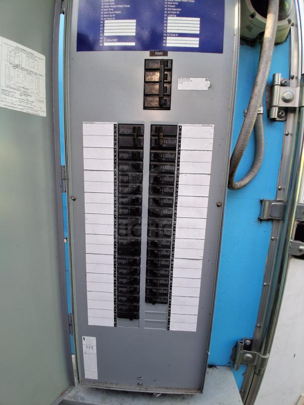 Electrical panel inside commercial kitchen trailer with labeled circuit breakers and specifications, in good condition.