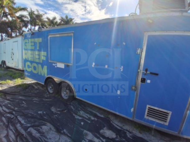 Blue commercial kitchen trailer with order window, equipped with grease hood, dual fryers, griddle, burner cooktop, and refrigeration.