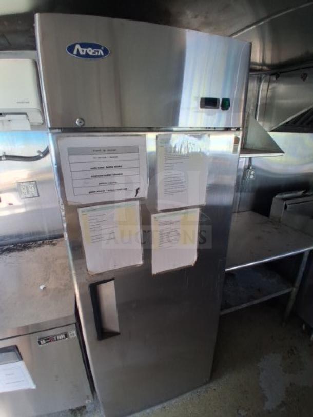 Commercial kitchen trailer interior with large order window, grease hood, dual fryers, griddle, burner cooktop, full refrigeration suite.