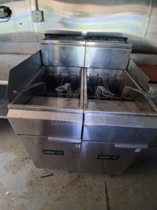 Commercial kitchen trailer with stainless dual fryers, labeled "Asber", in used condition, featuring small grease stains.