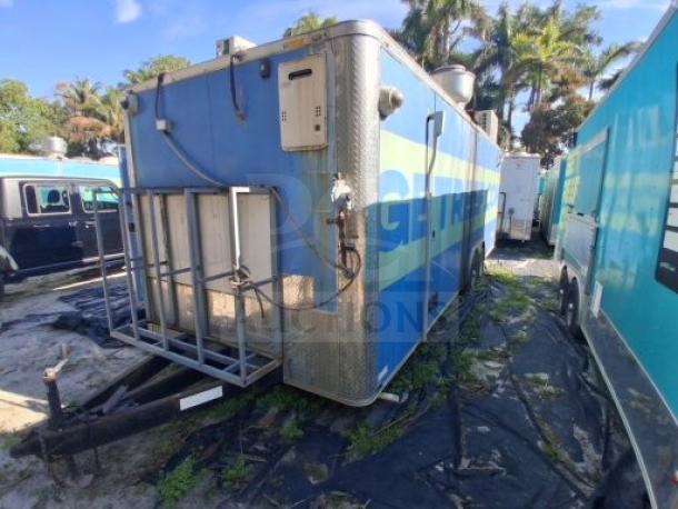 Commercial kitchen trailer with large order window, equipped with grease hood, dual fryers, griddle, burner cooktop, and refrigeration suite.
