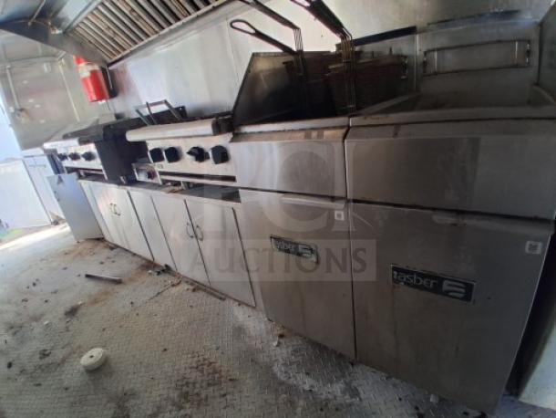 Commercial food trailer kitchen interior with FryMaster and Zesto appliances, stainless steel counters, and overhead ventilation.