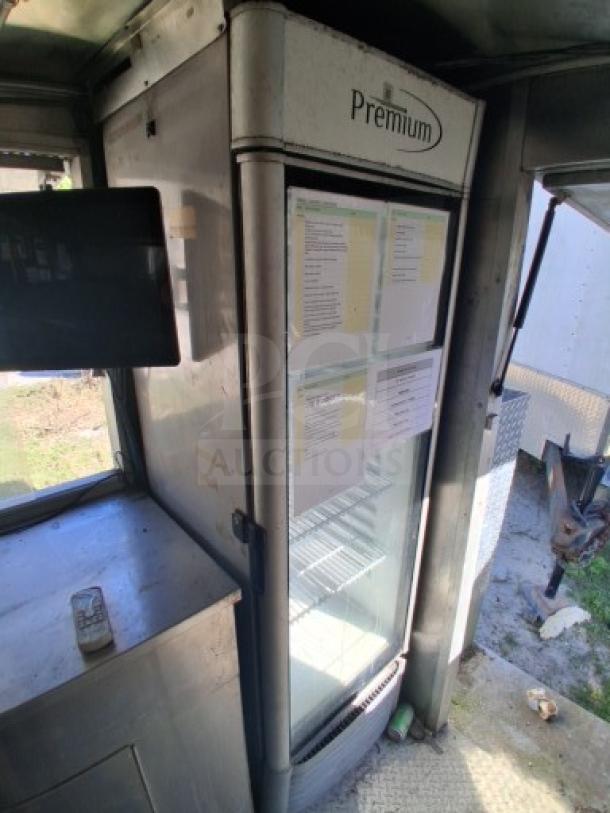 Interior of a food trailer featuring a Premium branded commercial refrigerator, visible documents on the door, and workspace areas.