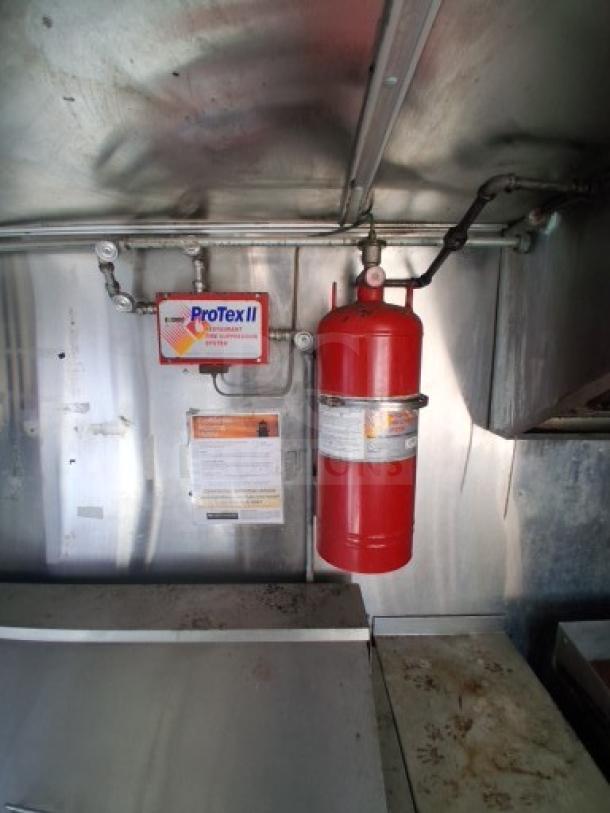Food trailer interior showing a ProTex II fire suppression system. Stainless steel surfaces indicate commercial-grade materials.