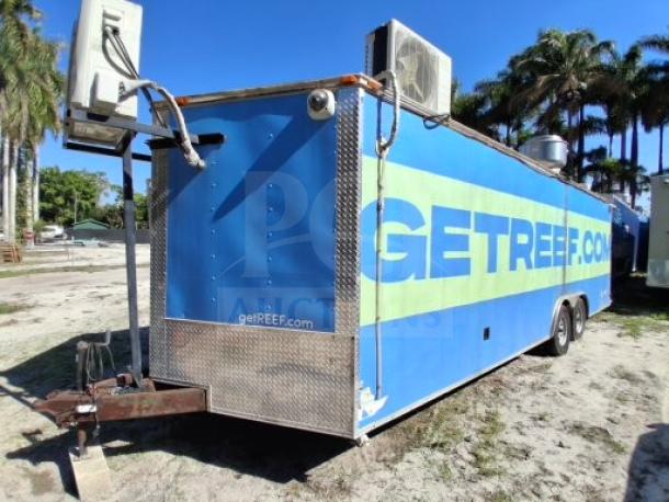 Blue food trailer with "GET REEF.COM" branding, equipped for commercial use. Features AC units, dual axles, robust utility setup.