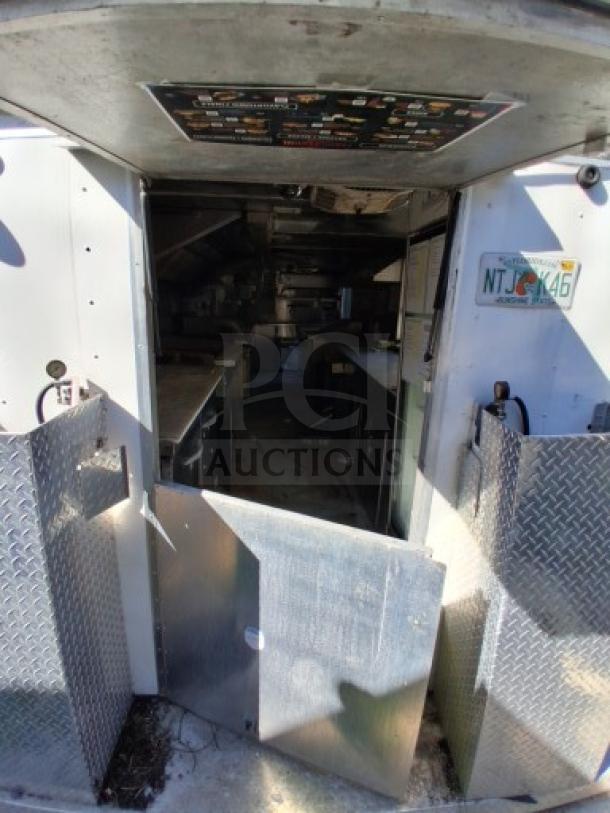 Food trailer interior with commercial kitchen equipment, diamond plate walls, and utility systems. Includes safety features. Needs improvements for full use.