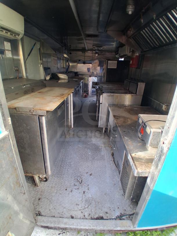 Mobile kitchen trailer with commercial refrigeration, fire suppression, climate control; interior features stainless steel appliances.