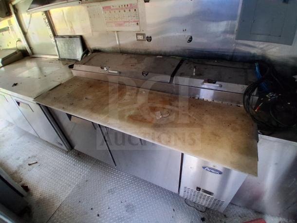 Fully loaded mobile kitchen interior with commercial refrigeration, fire suppression, and climate control. Some surface wear visible.