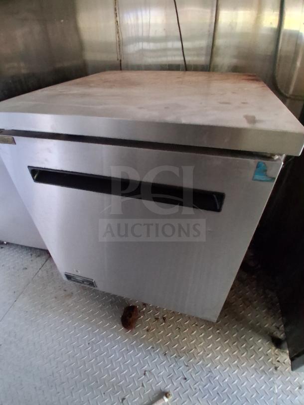 Commercial refrigerator in mobile kitchen trailer, stainless steel, good condition, equipped for high-volume food service.