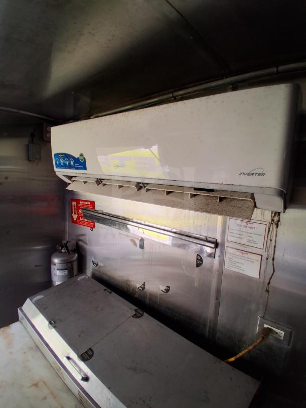 Inside view of a mobile kitchen trailer with commercial refrigeration, fire suppression system, and climate control unit.