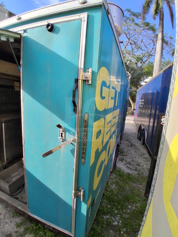 Blue mobile kitchen trailer featuring bold yellow lettering. Equipped with premium refrigeration and fire suppression.