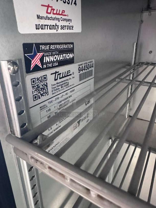 Stainless steel interior of True TUC-27G-LP-HC~FGD01 refrigerator. Labels show model, 115V power, and "Made in USA" innovation branding.