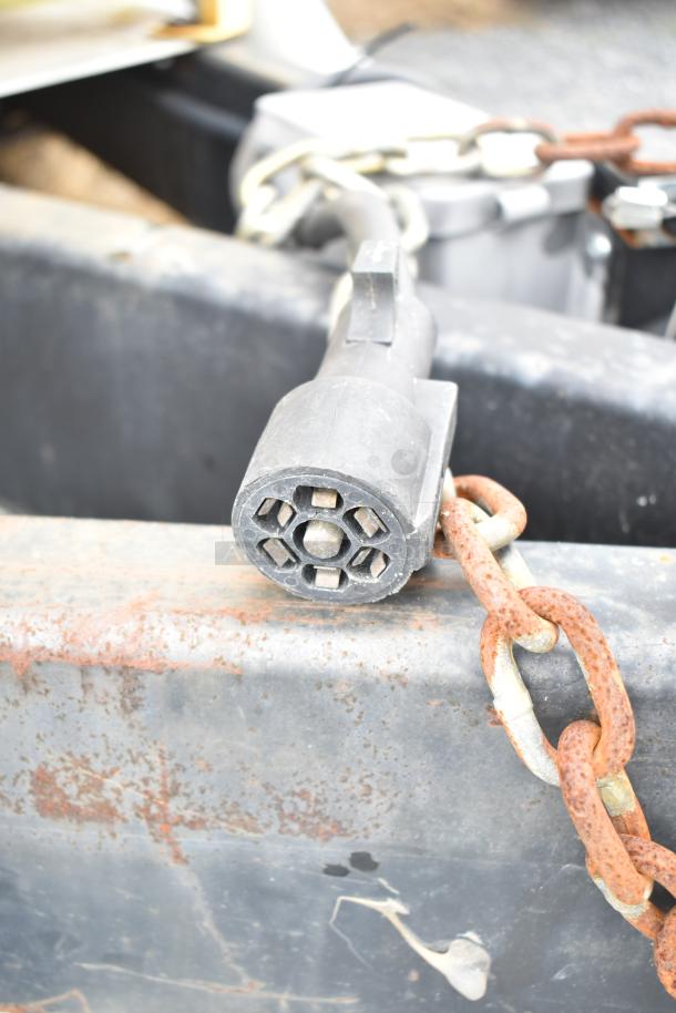 Commercial mobile kitchen trailer coupler with attached safety chain; trailer features CaptiveAire hood and Pitco fryers.