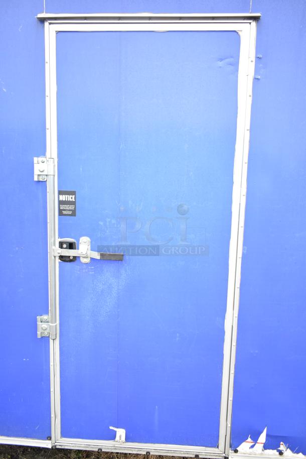 Blue commercial mobile kitchen trailer door with silver trim and handle, featuring a "NOTICE" sign adjacently.
