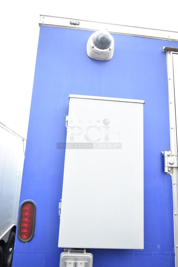 Commercial mobile kitchen trailer, blue exterior, features CaptiveAire hood, Pitco fryers, refrigeration, security camera and light.