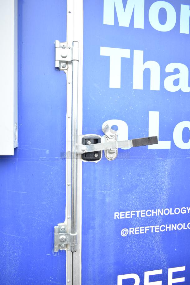 Blue mobile kitchen trailer door with metal latch. Branding reads "REEF TECHNOLOGY" and Twitter handle "@REEFTECHNOLOGY".