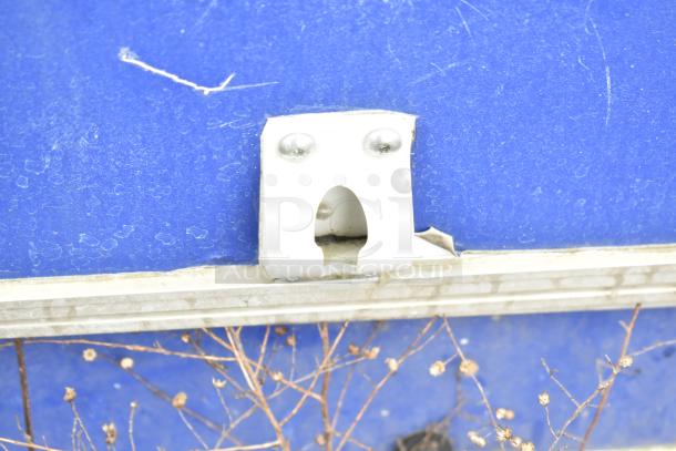 Blue exterior of a mobile kitchen trailer with a visible metal latch. The surface shows wear and signs of use.