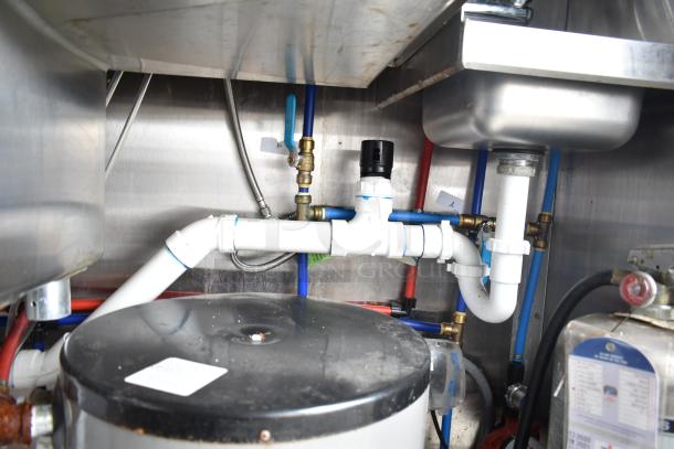 Interior plumbing and piping of a commercial mobile kitchen trailer, showcasing connections and equipment.